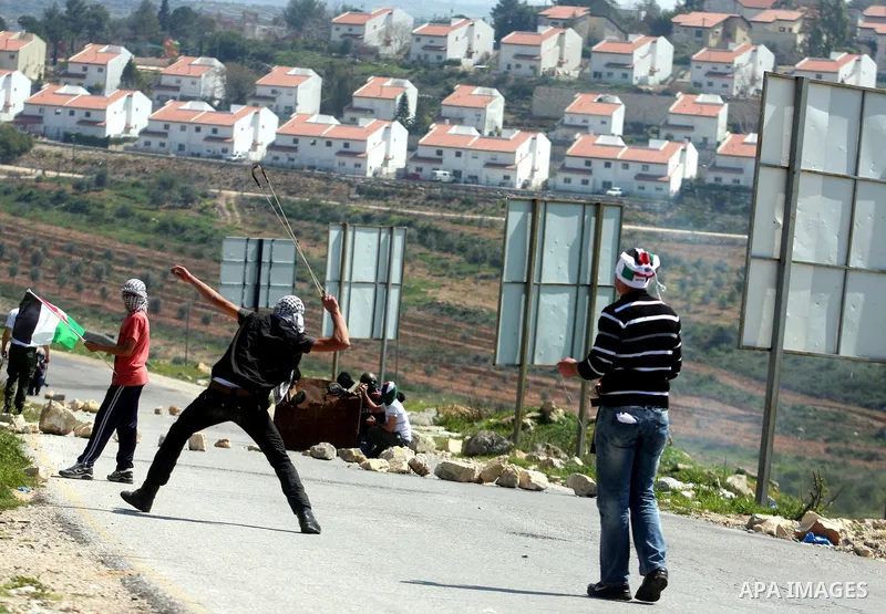 A Palestinian protester swings a sling at Israeli troops during a protest against the expansion of the nearby Jewish settlement of Halamish in the West Bank village of Nabi Saleh, near Ramallah, Friday, March 23, 2012. P...