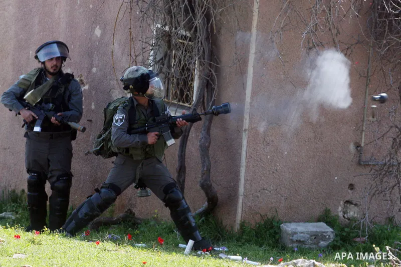 An Israeli soldier fires tear gas during clashes with Palestinian and foreign protestors in the occupied West Bank village of Nabi Saleh, near Ramallah, on March 23, 2012, following a protest against Palestinian land con...