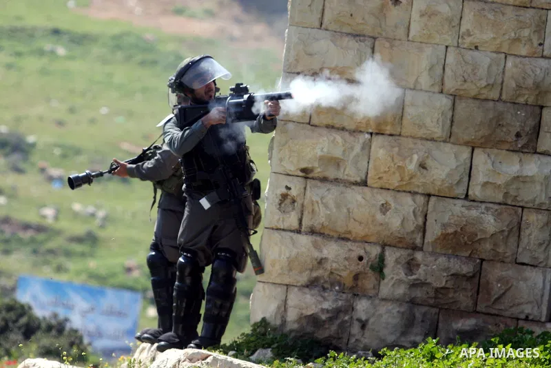 An Israeli soldier fires tear gas during clashes with Palestinian and foreign protestors in the occupied West Bank village of Nabi Saleh, near Ramallah, on March 23, 2012, following a protest against Palestinian land con...