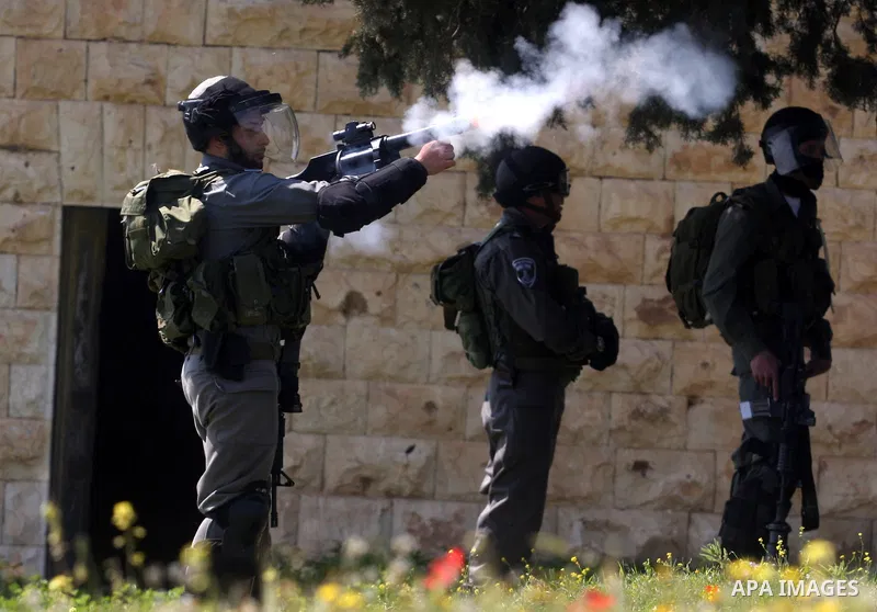 An Israeli soldier fires tear gas during clashes with Palestinian and foreign protestors in the occupied West Bank village of Nabi Saleh, near Ramallah, on March 23, 2012, following a protest against Palestinian land con...