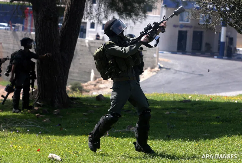 An Israeli soldier fires tear gas during clashes with Palestinian and foreign protestors in the occupied West Bank village of Nabi Saleh, near Ramallah, on March 23, 2012, following a protest against Palestinian land con...