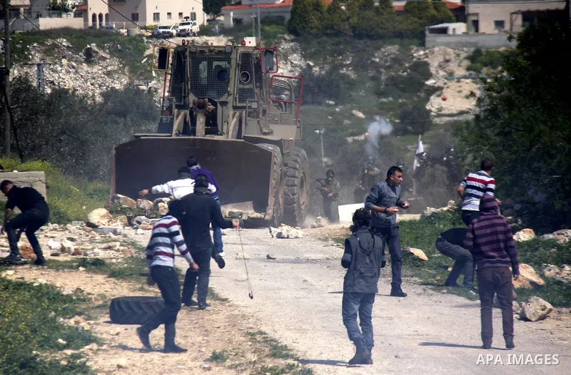 Palestinian protesters run away from a Israeli military vehicle spraying foul smelling water during clashes at a demonstration against the closure of a road for Palestinians in the West Bank village of Kfar Kadum, near N...