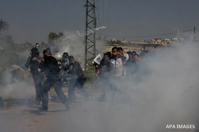 Palestinian protesters run away from a Israeli military vehicle spraying foul smelling water during clashes at a demonstration against the closure of a road for Palestinians in the West Bank village of Kfar Kadum, near N...