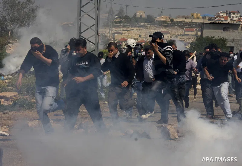 Palestinian protesters run away from a Israeli military vehicle spraying foul smelling water during clashes at a demonstration against the closure of a road for Palestinians in the West Bank village of Kfar Kadum, near N...