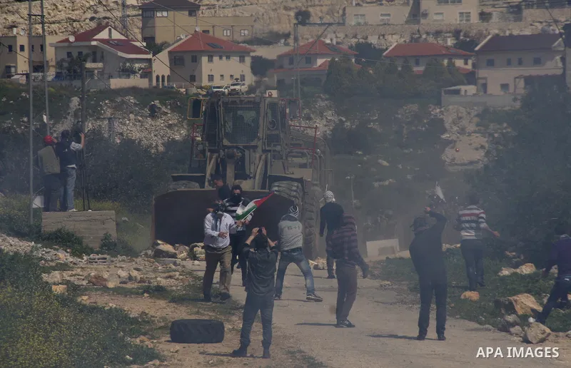 A Palestinian protester throws stones towards Israeli soldiers on March 23, 2012, during a protest against the closure of a road during the second Intifada (began late September 2000) by Jewish settlers from the nearby s...