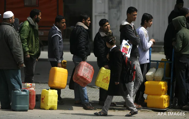 Palestinians wait to fill containers with fuel at a petrol station in Rafah on the southern Gaza Strip March 24, 2012. Palestinians in the Gaza Strip are suffering a crisis of dry petrol pumps and frequent blackouts trig...