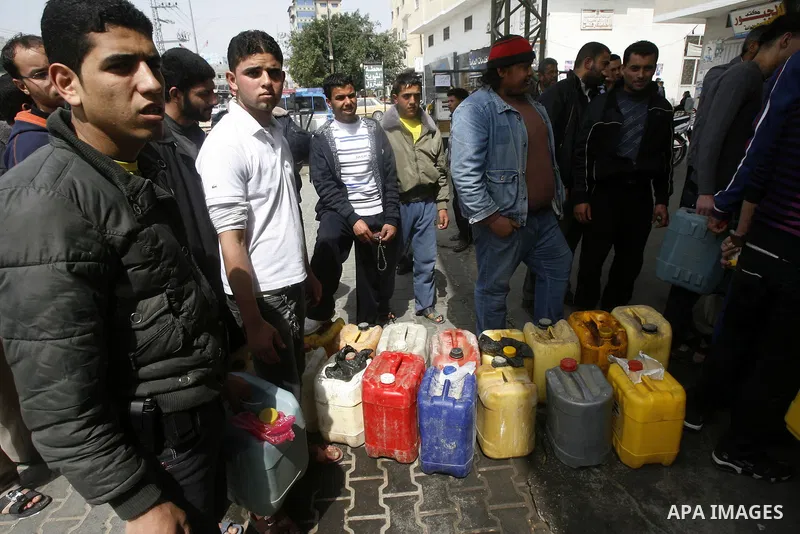 Palestinians wait to fill containers with fuel at a petrol station in Rafah on the southern Gaza Strip March 24, 2012. Palestinians in the Gaza Strip are suffering a crisis of dry petrol pumps and frequent blackouts trig...