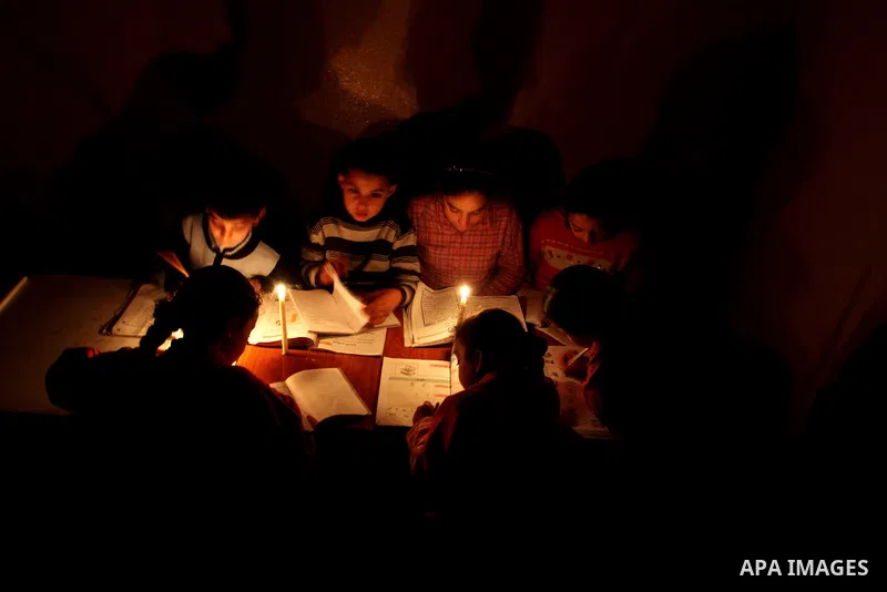 Palestinian children use a candle light during a power cut in Jabaliya refugee camp in the northern Gaza Strip 24 March 2012. The only remaining power plant in the Gaza Strip halted working because it run out of fuel, ca...