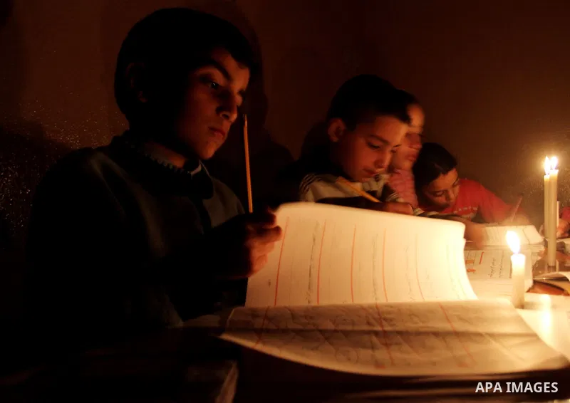 Palestinian children use a candle light during a power cut in Jabaliya refugee camp in the northern Gaza Strip 24 March 2012. The only remaining power plant in the Gaza Strip halted working because it run out of fuel, ca...