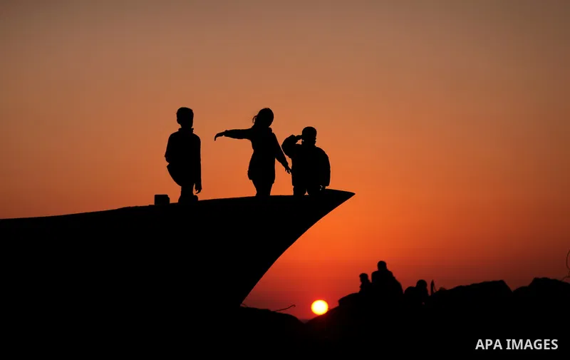 Palestinians enjoy their times during the sunset in Gaza fishing seaport, on March 23, 2012. Photo by Emad Nassar