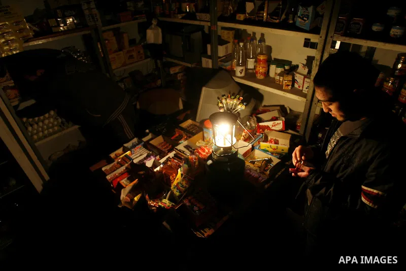 A Palestinian man sits in his shop during a blackout in Rafah on the southern Gaza Strip on, 26 March 2012. The only remaining power plant in the Gaza Strip halted working because it run out of fuel, causing a blackout,...