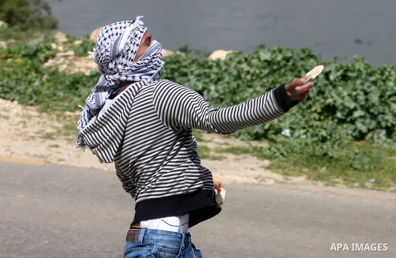 Palestinian demonstrators hurls stones at Israel troops, background, during clashes outside the Ofer military prison, near the West Bank city of Ramallah Monday, March. 26,2012. Clashes erupted during a demonstration cal...