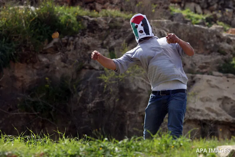 Palestinian demonstrators hurls stones at Israel troops, background, during clashes outside the Ofer military prison, near the West Bank city of Ramallah Monday, March. 26,2012. Clashes erupted during a demonstration cal...