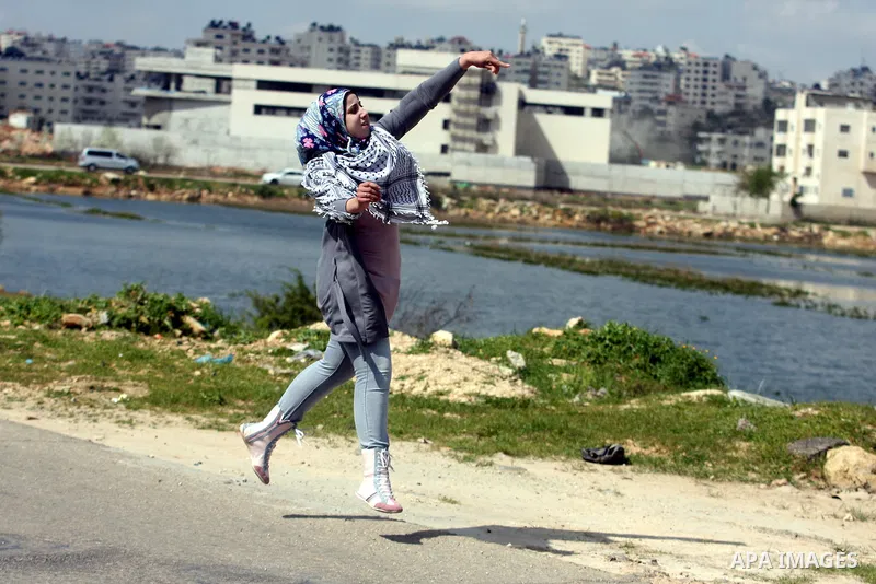 Palestinian demonstrators hurls stones at Israel troops, background, during clashes outside the Ofer military prison, near the West Bank city of Ramallah Monday, March. 26,2012. Clashes erupted during a demonstration cal...