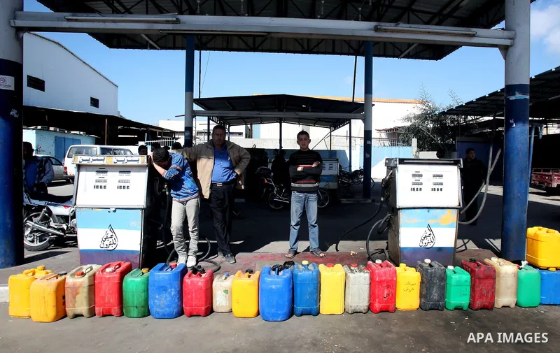 Palestinians wait to fill containers with fuel at a petrol station in Gaza City March 26, 2012. Palestinians in the Gaza Strip are suffering a crisis of dry petrol pumps and frequent blackouts triggered by a fuel supply...