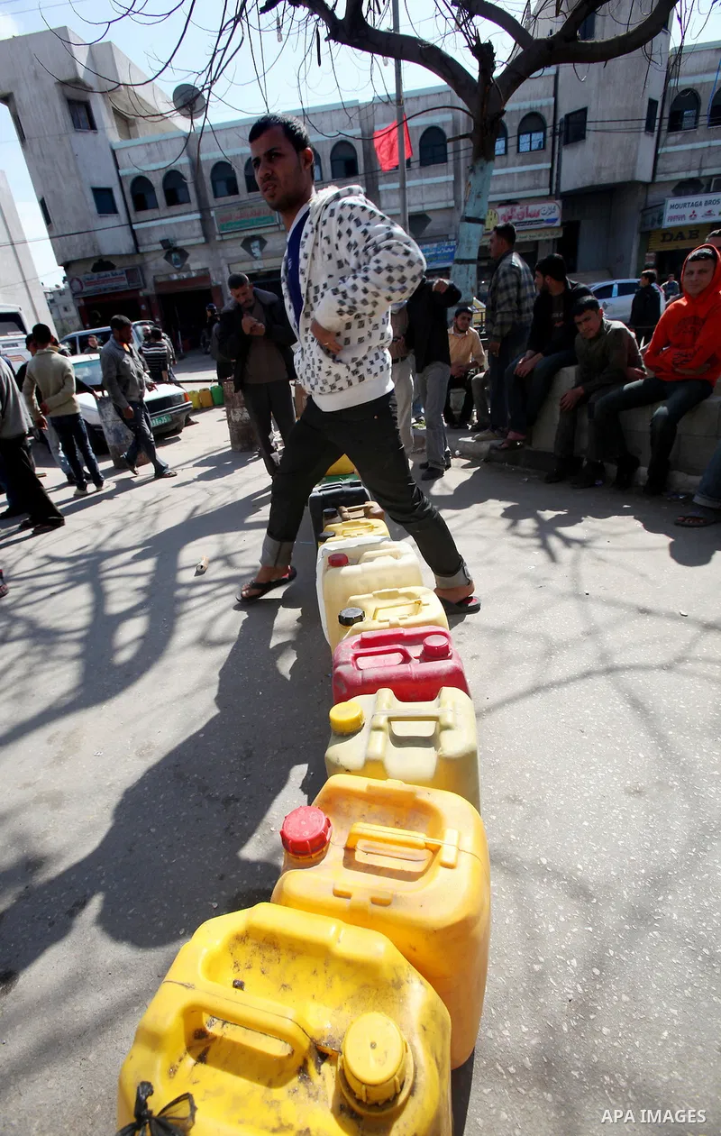 Palestinians wait to fill containers with fuel at a petrol station in Gaza City March 26, 2012. Palestinians in the Gaza Strip are suffering a crisis of dry petrol pumps and frequent blackouts triggered by a fuel supply...