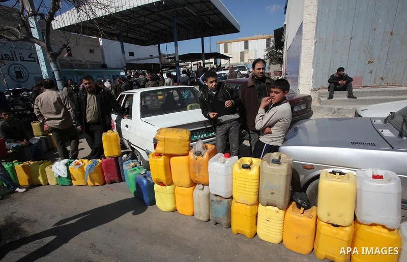 Palestinians wait to fill containers with fuel at a petrol station in Gaza City March 26, 2012. Palestinians in the Gaza Strip are suffering a crisis of dry petrol pumps and frequent blackouts triggered by a fuel supply...