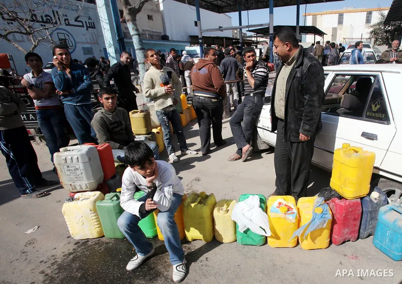 Palestinians wait to fill containers with fuel at a petrol station in Gaza City March 26, 2012. Palestinians in the Gaza Strip are suffering a crisis of dry petrol pumps and frequent blackouts triggered by a fuel supply...