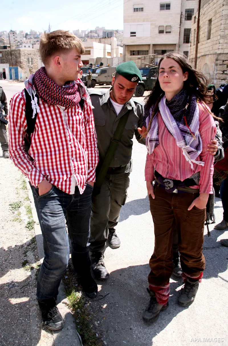 Israeli settlers walk past Israeli border policemen standing guard outside an occupied Palestinian house after dozens of Jewish settlers took over the property overnight, claiming they have legal ownership, in the occupi...