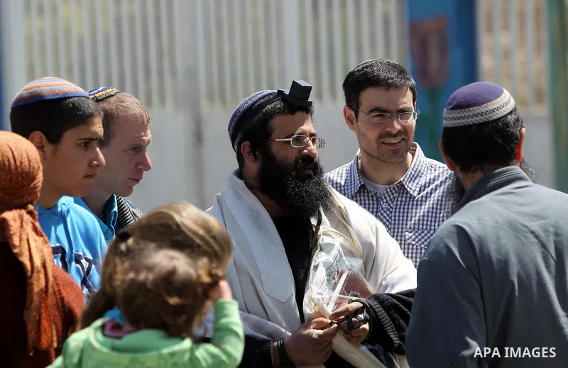 Israeli settlers stand at the entrance to an occupied Palestinian house after dozens of Jewish settlers took over the property overnight, claiming they have legal ownership, in the occupied West Bank city of Hebron on Ma...