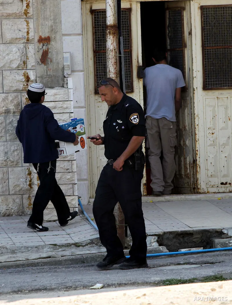 Israeli settlers stand at the entrance to an occupied Palestinian house after dozens of Jewish settlers took over the property overnight, claiming they have legal ownership, in the occupied West Bank city of Hebron on Ma...