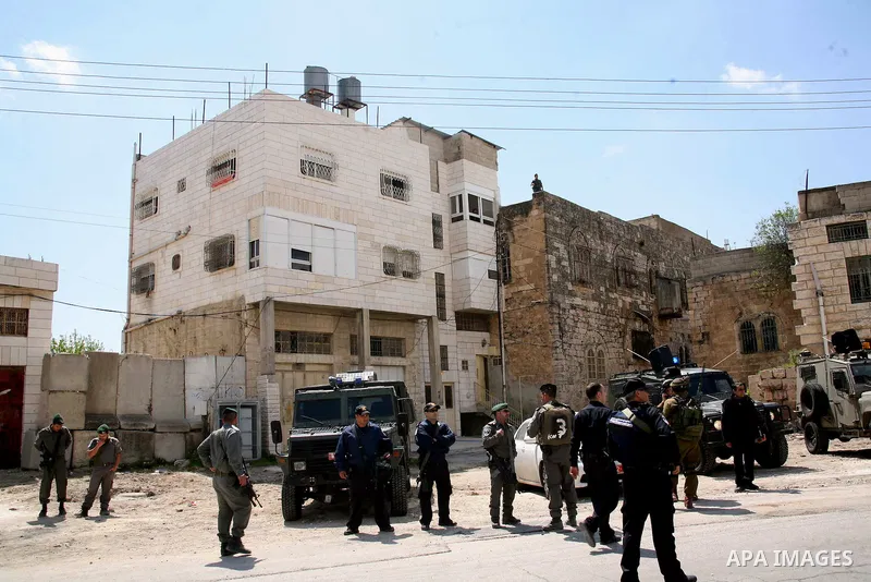Israeli settlers walk past Israeli border policemen standing guard outside an occupied Palestinian house after dozens of Jewish settlers took over the property overnight, claiming they have legal ownership, in the occupi...