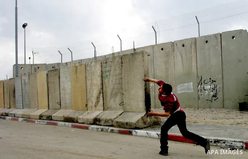 A Palestinian boy throw stones towards Israeli soldiers during clashes at the Qalandia checkpoint between the West Bank city of Ramallah and Jerusalem, on 29 March 2012. Photo by Mahfouz Abu Turk