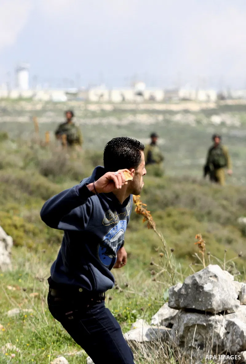A Palestinian protester throws stones at Israeli soldiers during a demonstration to mark the anniversary of Land Day in the village Iraq Burin, near town of Nablus in the occupied Israeli West bank on March 30, 2012. Lan...