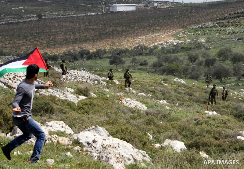 A Palestinian protester throws stones at Israeli soldiers during a demonstration to mark the anniversary of Land Day in the village Iraq Burin, near town of Nablus in the occupied Israeli West bank on March 30, 2012. Lan...