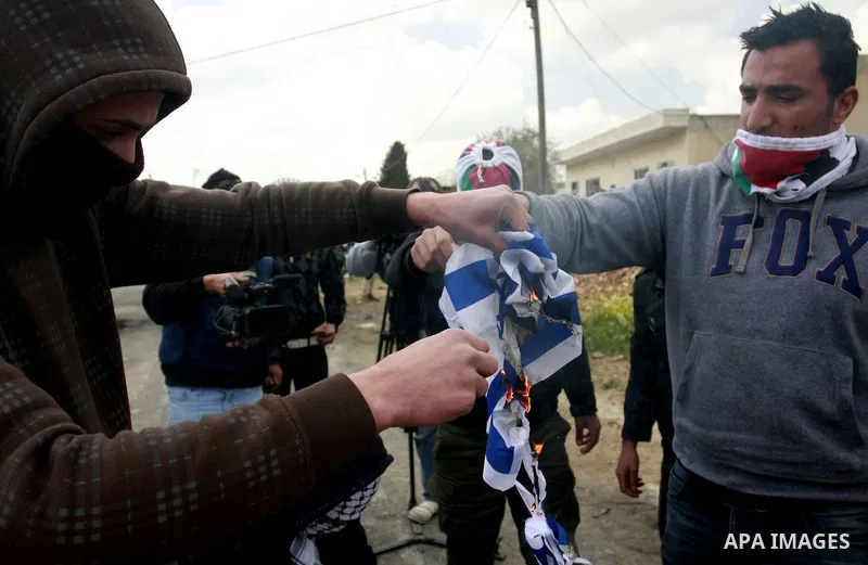 Palestinian protesters burn the Israeli flag during a demonstration to mark the anniversary of Land Day in the village Kafr Qaddum, close to the northern town of Nablus in the occupied Israeli West bank on March 30, 2012...