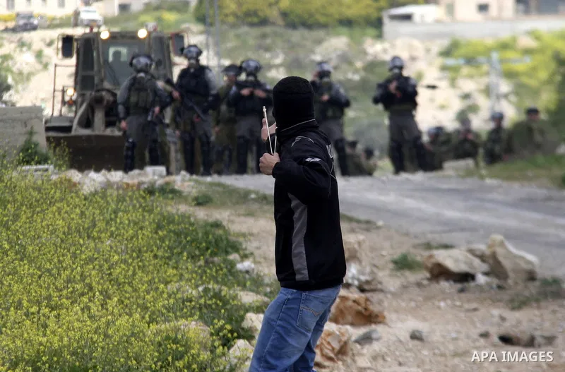 A Palestinian protester throws stones at Israeli soldiers during a demonstration to mark the anniversary of Land Day in the village Kafr Qaddum, close to the northern town of Nablus in the occupied Israeli West bank on M...
