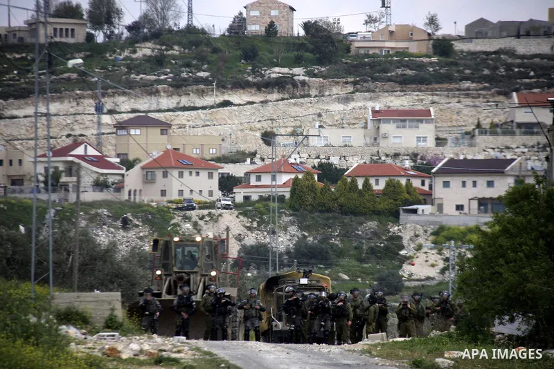 Israeli soldiers stand guards as Palestinian protesters throw stones during a demonstration to mark the anniversary of Land Day in the village Kafr Qaddum, close to the northern town of Nablus in the occupied Israeli Wes...