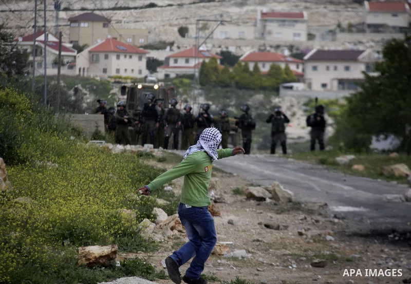 A Palestinian protester throws stones at Israeli soldiers during a demonstration to mark the anniversary of Land Day in the village Kafr Qaddum, close to the northern town of Nablus in the occupied Israeli West bank on M...