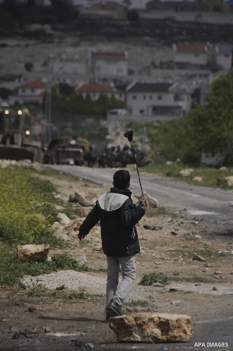 A Palestinian protester throws stones at Israeli soldiers during a demonstration to mark the anniversary of Land Day in the village Kafr Qaddum, close to the northern town of Nablus in the occupied Israeli West bank on M...