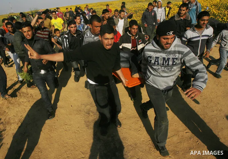 Palestinians carry a wounded protester during clashes with Israeli security forces at a protest near the border between Israel and southern Gaza Strip March 30, 2012. Israeli security forces fired rubber bullets, tear ga...