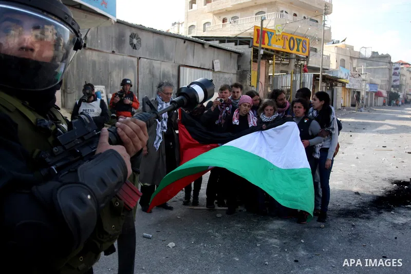 International peace activists hold the Palestinian flag as they Israeli police officers during the commemoration of Land Day in Qalandia which lies between Jerusalem and the West Bank city of Ramallah on March 30, 2012....