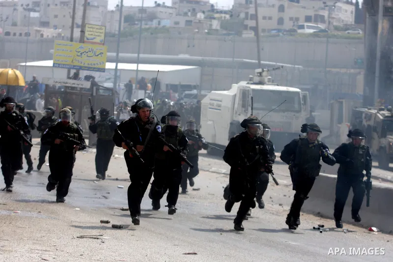 Israeli police officers fire rubber bullets at Palestinians protesters as clashes errupted during the commemoration of Land Day in Qalandia which lies between Jerusalem and the West Bank city of Ramallah on March 30, 201...
