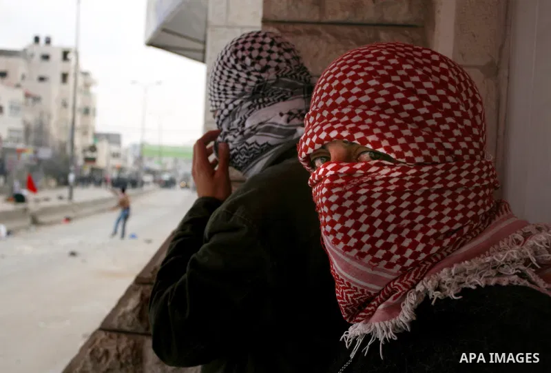 A masked Palestinian protester holds his national flag as he commemorates Land Day in Qalandia which lies between Jerusalem and the West Bank city of Ramallah on March 30, 2012. Land Day marks the annual event that comme...