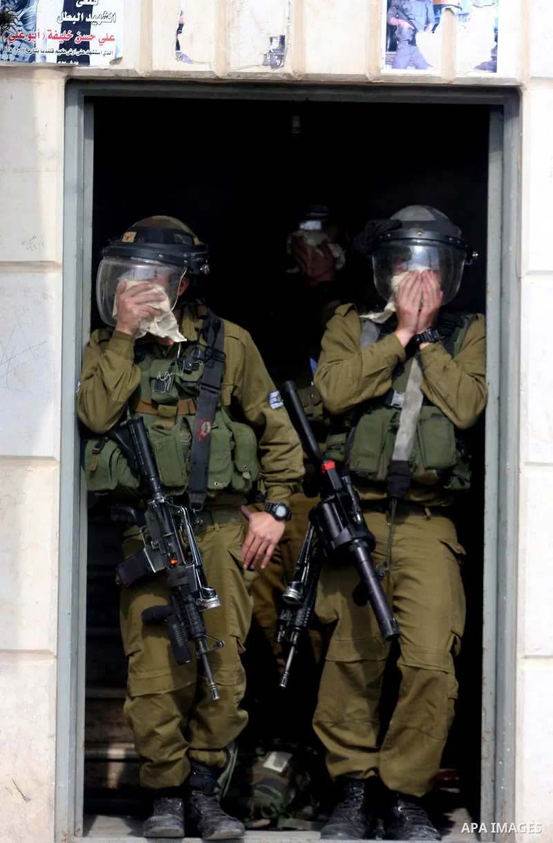 Israeli soldiers cover their noses from the residue of tear gas during nearby clashes between Israeli soldiers and Palestinian protesters as they mark the anniversary of Land Day in Qalandia which lies between Jerusalem...