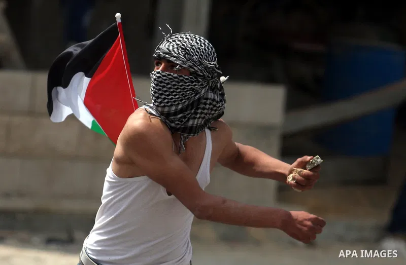 A Palestinian protester uses a sling to hurl stones at Israeli security officers during clashes at a demonstration marking Land Day, at Qalandiya checkpoint, near the West Bank city of Ramallah March 30, 2012. Israeli se...