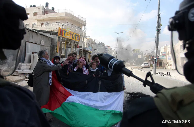International peace activists hold the Palestinian flag as they Israeli police officers during the commemoration of Land Day in Qalandia which lies between Jerusalem and the West Bank city of Ramallah on March 30, 2012....