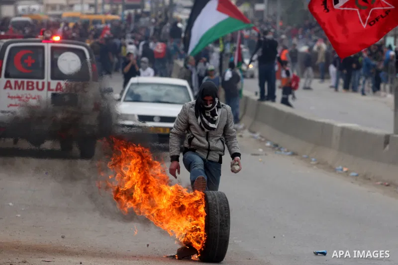 A Palestinian youth rolls a flaming car tire towards Israeli soldiers during a protest to mark the anniversary of Land Day in Qalandia which lies between Jerusalem and the West Bank city of Ramallah on March 30, 2012. La...