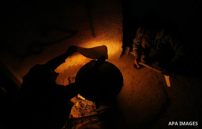 Palestinians prepare freshly baked pita bread at a traditional bakery using a wood burning stove in the Rafah refugee camp in the southern Gaza Strip on March 31, 2012. Gaza is experiencing a major electricity crisis bec...