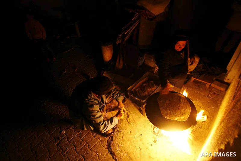 Palestinians prepare freshly baked pita bread at a traditional bakery using a wood burning stove in the Rafah refugee camp in the southern Gaza Strip on March 31, 2012. Gaza is experiencing a major electricity crisis bec...