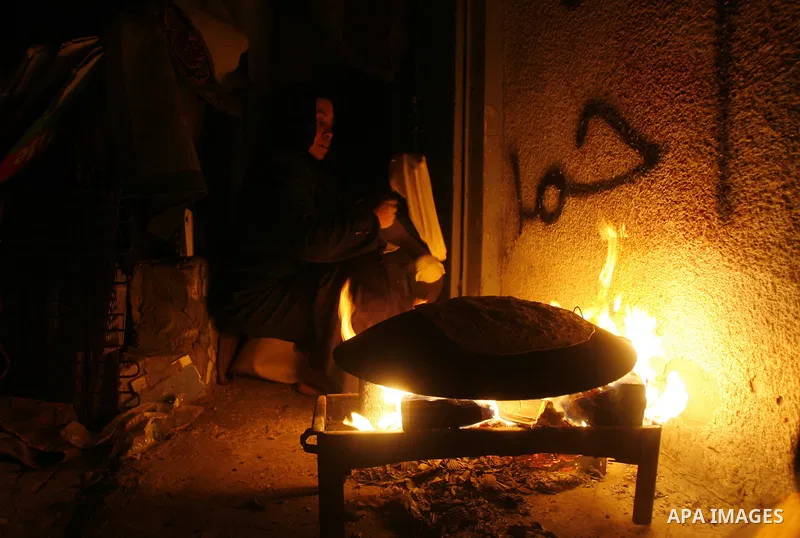 Palestinians prepare freshly baked pita bread at a traditional bakery using a wood burning stove in the Rafah refugee camp in the southern Gaza Strip on March 31, 2012. Gaza is experiencing a major electricity crisis bec...