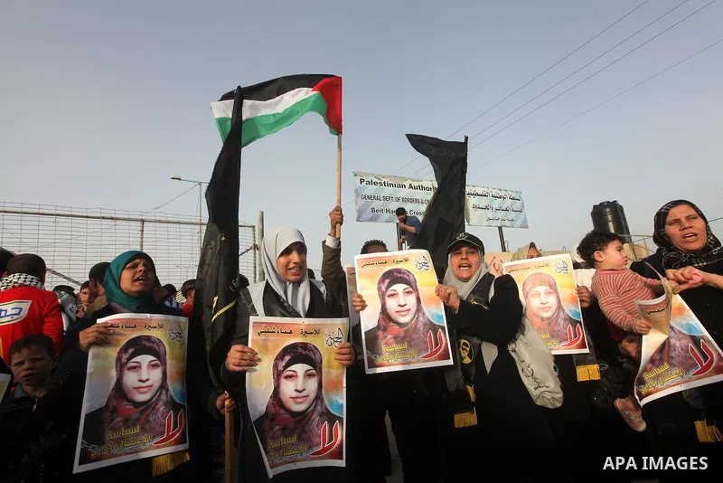 Palestinians hold posters of Hanaa Shalabi, a prisoner who spent 43 days on hunger strike, as they wait to greet her near the Erez border crossing between Israel and the northern Gaza Strip on April 1, 2012. Shalabi, who...