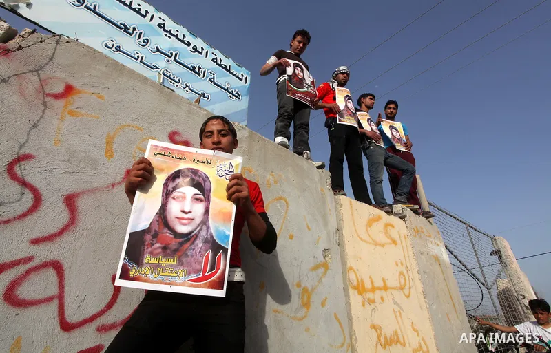 Palestinians hold posters of Hanaa Shalabi, a prisoner who spent 43 days on hunger strike, as they wait to greet her near the Erez border crossing between Israel and the northern Gaza Strip on April 1, 2012. Shalabi, who...