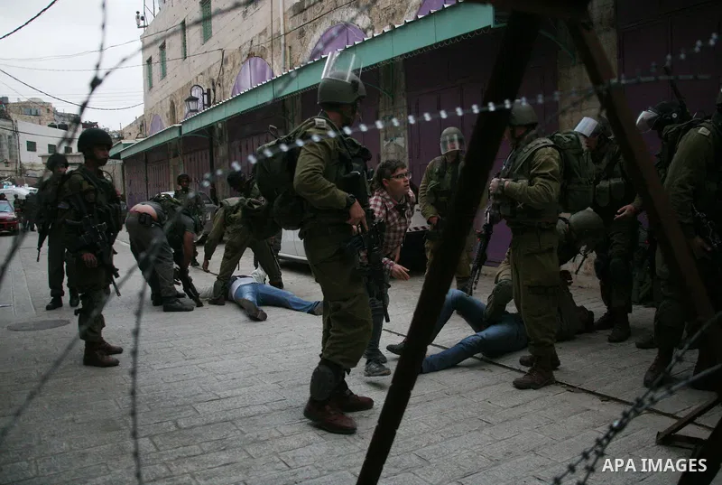 Israeli policemen and soldiers detain Palestinian protesters and foreign activists on April 01, 2012, after they took refuge in an abandoned house and fly a Palestinian flag on the rooftop of the building near the Beit R...