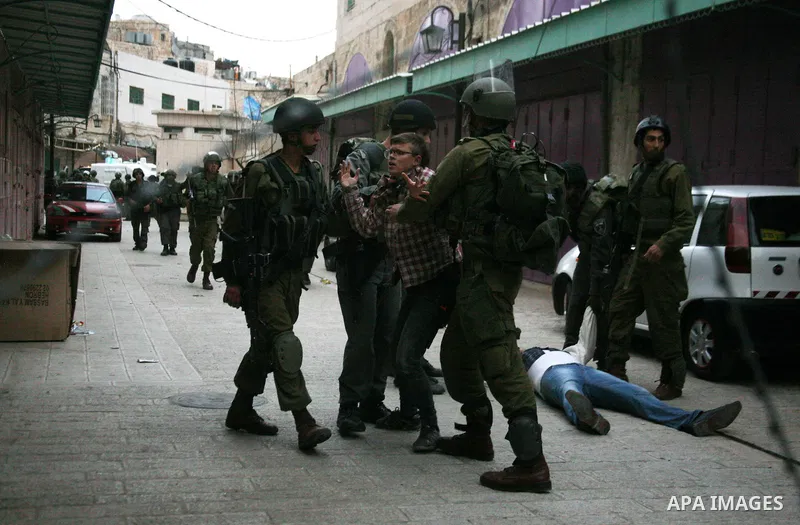 Israeli policemen and soldiers detain Palestinian protesters and foreign activists on April 01, 2012, after they took refuge in an abandoned house and fly a Palestinian flag on the rooftop of the building near the Beit R...