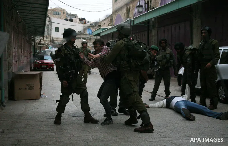 Israeli policemen and soldiers detain Palestinian protesters and foreign activists on April 01, 2012, after they took refuge in an abandoned house and fly a Palestinian flag on the rooftop of the building near the Beit R...